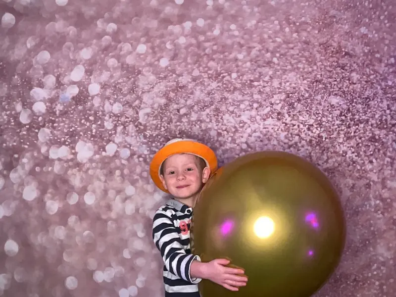 Kind mit Hut vor Glitzer-Leinwand in der Fotobox